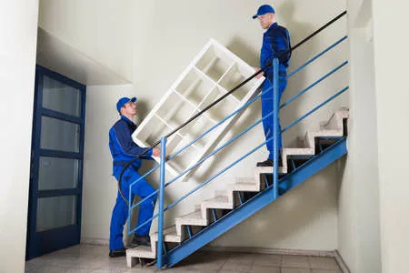 عمال شركة عرب موورز ہب ينقلون قطعة أثاث كبيرة عبر الدرج ضمن خدمات شركة نقل عفش بجازان باحترافية وأمان