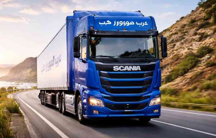 شاحنة نقل عفش زرقاء حديثة تابعة لشركة عرب موورز ہب تسير على طريق جبلي سريع لتقديم خدمات شركه نقل عفش بخميس مشيط باحترافية وأمان.