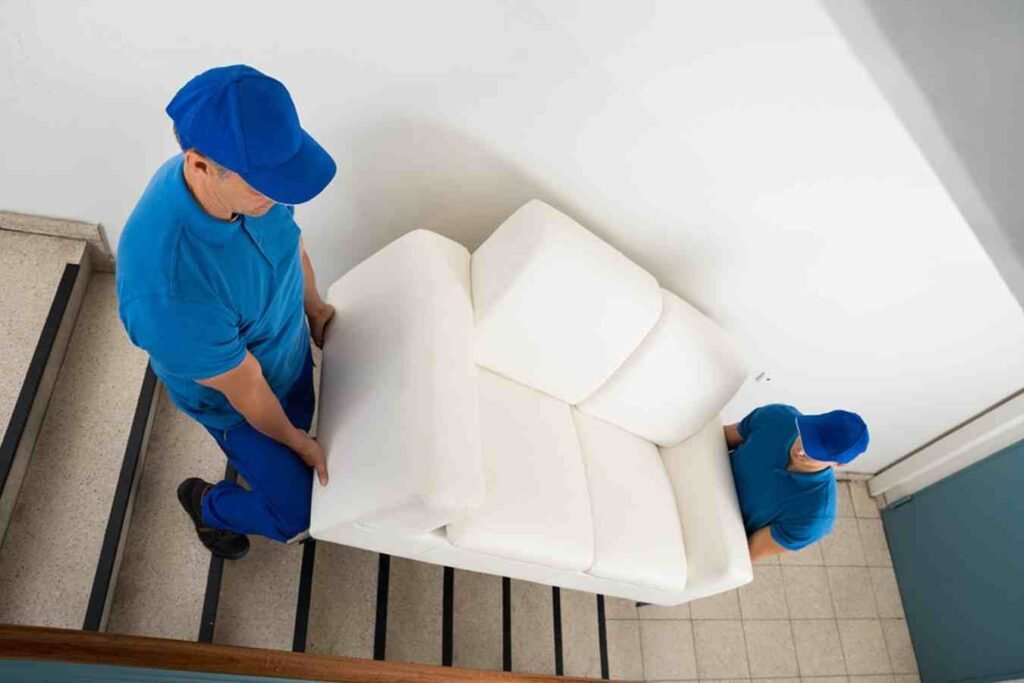 عمال نقل عفش بريدة من عرب موورز ہب يحملون كنبة بحذر على الدرج مع ضمان الحماية الكاملة للأثاث
